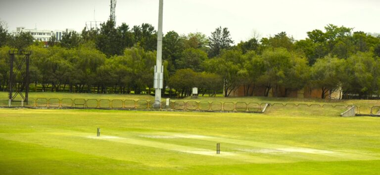 Wide-angle view of a cricket ground under natural daylight.